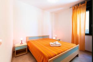 a bedroom with a bed with orange sheets and a window at Appartamenti Cavour cod C in Villasimius