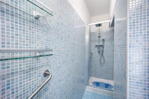 a blue tiled bathroom with a shower and a toilet at Edda's apartment in Altare +15 photos