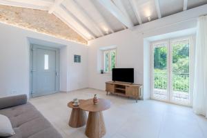 a living room with a couch and a tv at The Olive Yard Corfu Sidari in Karousádes