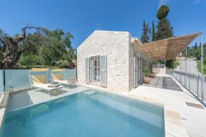 a swimming pool with two chairs and a house at The Olive Yard Corfu Sidari in Karousádes