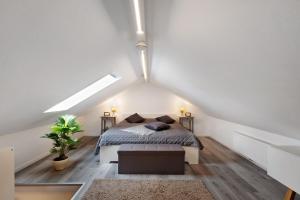 a white attic bedroom with a bed and a plant at Küsten-Bude in Elmenhorst