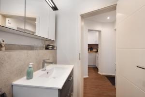 a white kitchen with a sink and a counter at Küsten-Bude in Elmenhorst +13 photos