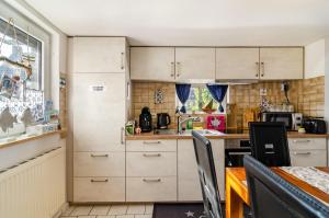 a small kitchen with white cabinets and a table at Ferienhaus Segelboot in Krummhörn