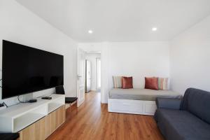 a living room with a couch and a flat screen tv at Telmus Villa 1 andar in Monte Gordo