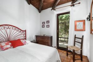 a bedroom with a bed and a chair and a window at Villa Romana in Costa Rei