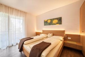 a bedroom with a large bed with a large window at Schnitzer Ferienwohnung Löwenzahn in Rablà