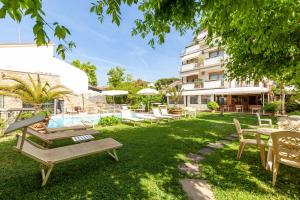 a garden with tables and chairs and a building at Appartamento Bacco in Lido di Camaiore