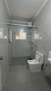 a white bathroom with a shower and a toilet at Yak villa in Kushālnagar