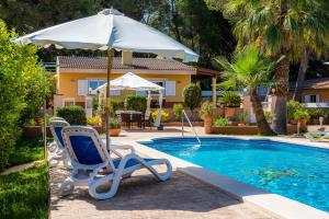 a chair and an umbrella next to a swimming pool at S'oratge in Can Picafort