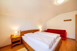 a bedroom with a large bed and a red couch at Gasserhof Ferienwohnung Jonagold in Caines +26 photos