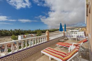 a balcony with chairs and umbrellas and a view of the ocean at Casa Marron in Costa Calma