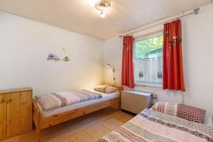 a bedroom with two beds and a window with red curtains at Ferienbungalow 2 in Boitzenburg in Boitzenburg