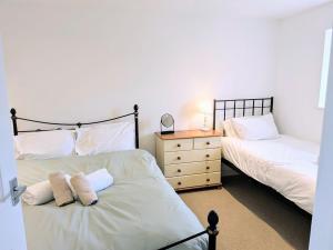 a bedroom with two beds and a dresser with a mirror at Salton Lodge Barns in Great Edston
