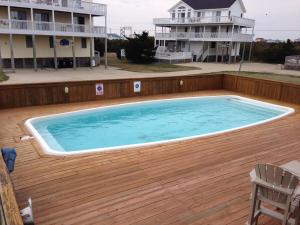 a swimming pool on a deck with a house in the background at Carolina Breeze in Rodanthe