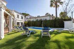 a group of chairs sitting on the grass near a swimming pool at Villa Eden Nerja in Nerja