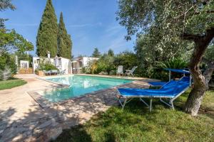 a pool with two blue chairs next to a tree at Villa Massa in Polignano a Mare