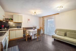 a kitchen and living room with a table and a couch at Gartnerhof Apt Glücksklee in Colle Isarco +15 photos