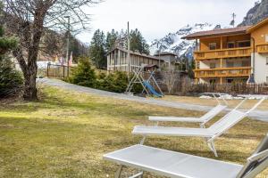 a couple of white chairs in a yard with a building at Gartnerhof Apt Glücksklee in Colle Isarco