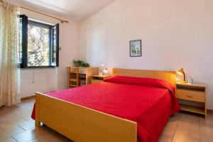 a bedroom with a red bed and a window at Fantastico quadrilocale vista mare in Trinità d'Agultu e Vignola