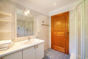 a bathroom with a sink and a mirror and a door at Rieglhof Apartment Geiernest in Curon Venosta
