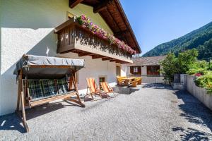 a patio with chairs and a balcony with flowers at Rieglhof Apartment Geiernest in Curon Venosta