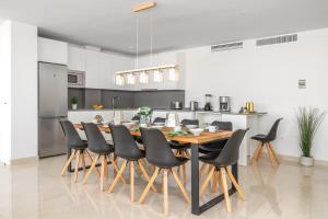 a kitchen with a wooden table and black chairs at Penthouse Banderas with own pool in La Cala de Mijas