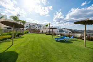 a blue bench sitting in a yard with umbrellas at Penthouse Banderas with own pool in La Cala de Mijas