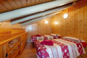 two beds in a room with wooden walls at Petite Maison des Alpes in Morgex