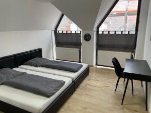 two beds in a room with a desk and two windows at Ferienwohnung Khorsandi Zwei in Coburg