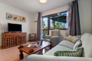 a living room with a couch and a tv at Oasis Bahia Fronte Piscine in Corralejo