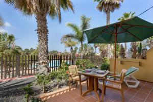 a patio with a table and chairs and an umbrella at Oasis Bahia Fronte Piscine in Corralejo