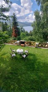 a table and chairs in a yard with a lake at Villa Freddie Mavrovo - Lakeview House in Mavrovo