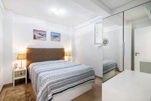 a white bedroom with a bed and a glass door at Paraná in Quarteira