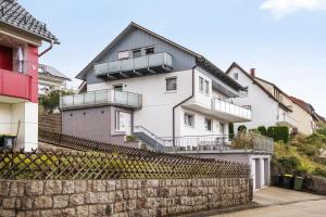 a white house with balconies on top of a stone wall at Ferienwohnung Windradblick in Schonach