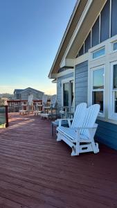 two white chairs sitting on a deck next to a house at Carolina Breeze in Rodanthe