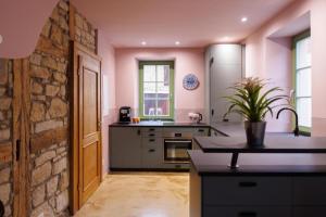 a kitchen with pink walls and a stone wall at Ferienhaus Monteverde in Meddersheim +15 photos