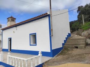 a white and blue building with stairs and a lighthouse at Casa da Mina in Mina do Bugalho
