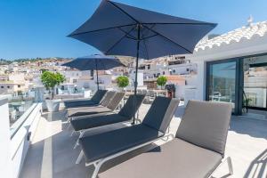 a row of chairs and an umbrella on a balcony at Spacious apartment in Cómpeta in Cómpeta
