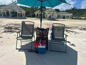 two chairs and an umbrella on the beach at Fisherman's Inn Hotel Silver Sands, Duncans Bay in Duncans
