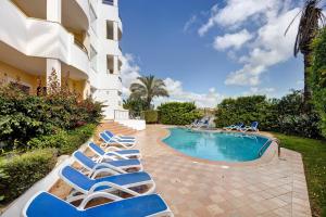 a group of lounge chairs next to a swimming pool at Chez Hélène et Paulo - Lagos in Lagos