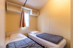 two beds in a small room with a window at Mobilhome Le Chataignier in Saint-Pompont