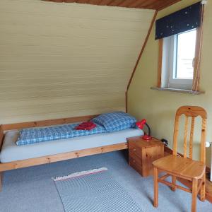 a bed in a room with a chair and a table at Ferienhaus Hadler in Kaiser Wilhelm Koog