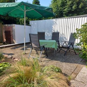 a green table and chairs under a green umbrella at Ferienhaus Hadler in Kaiser Wilhelm Koog