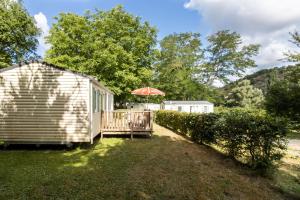 a small cabin with an umbrella in the yard at Mobilhome Le Chataignier in Saint-Pompont