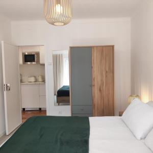 a bedroom with a white bed with a green blanket at Casa dos Avós in Cascais