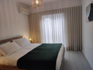 a bedroom with a large bed and a window at Casa dos Avós in Cascais