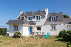 a large white house with a blue roof at Villa Nicole face mer in Trégunc