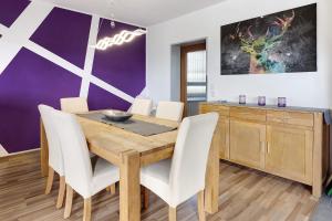 a dining room with a wooden table and white chairs at Sonnenblick in Lenzkirch