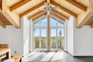 a living room with a ceiling fan and a large window at Cosy Home Allgäu in Haldenwang