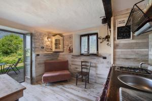 a kitchen with a sink and a counter with a chair at Casale La Selva Cottege piccolo in Piano Porlezza +14 photos
